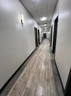 Same hallway after the final clean, with clear wood-look floors and clean walls